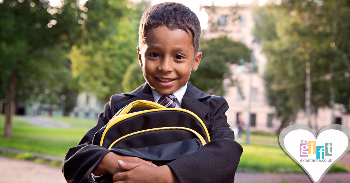 a little boy in a school uniform with a backpack all ready for school